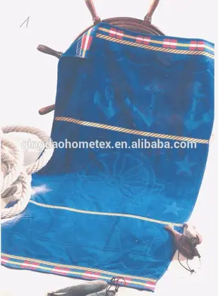 Blue nautical-patterned towel draped over a ship's wheel with rope, on a light background