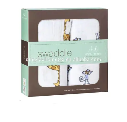 Packaged baby swaddle blankets with giraffe and monkey prints in a brown and mint box