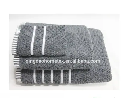 Stack of folded gray towels with white stripes, with BSCI and Confidence in Textiles certification logos below