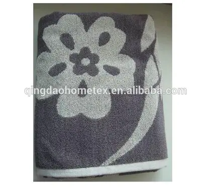 Gray folded towel with large white floral pattern on a plain surface