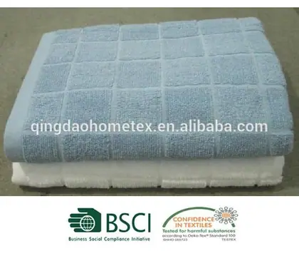 Folded light blue and white waffle-weave towels stacked on a plain surface, with certification logos below.