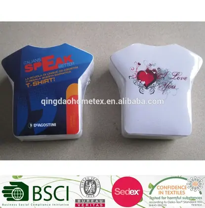Two t-shirt-shaped packaged items on a gray surface, one printed in blue with text, one white with heart design
