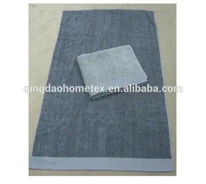 Navy herringbone towels with light grey borders, one folded on top of the other on a concrete floor