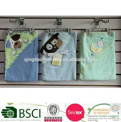 Three hooded baby towels in green and blue with animal appliques hanging on wall hooks
