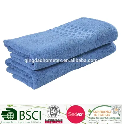 Stack of folded light blue terry towels with a textured dobby band, on a white background with certification logos below