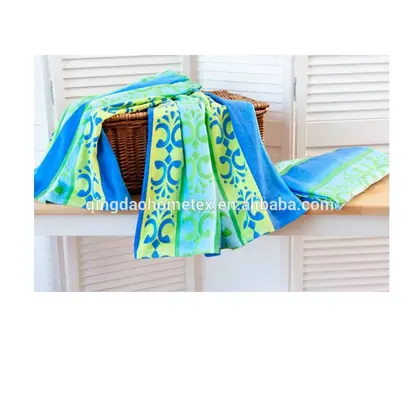 Colorful printed beach towels in blue and green draped over a wicker basket on a white wooden surface