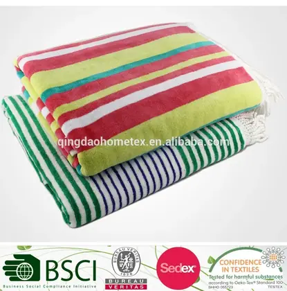 Two folded striped beach towels in green, pink, yellow, and teal on a white background with certification logos below.