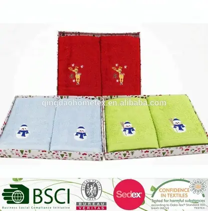 Three boxed two-piece embroidered towel sets in red, light blue, and green with reindeer and snowman designs