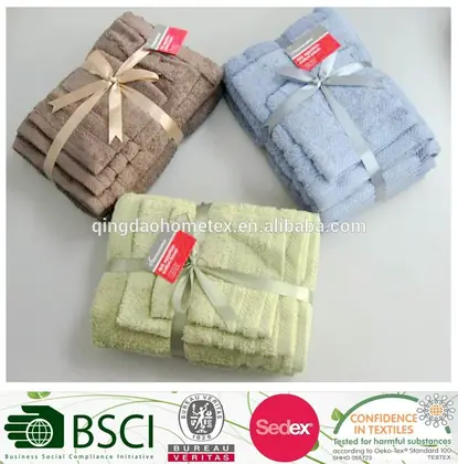 Three stacked towel sets in brown, blue, and green tied with ribbon bows on a white surface