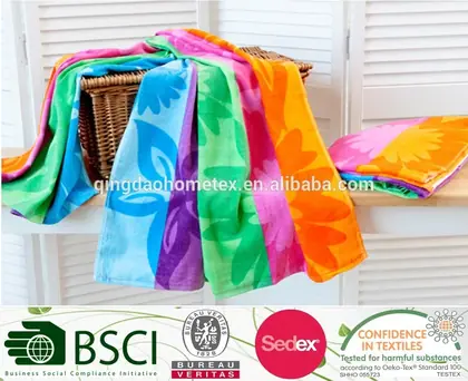 Colorful floral-patterned beach towels draped over a wicker basket with certification logos overlaid below