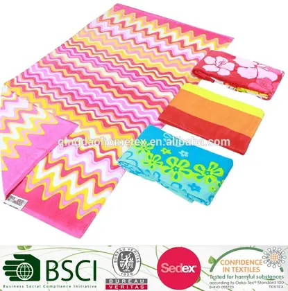 Collection of colorful printed beach towels with zigzag and floral patterns, folded and displayed with certification logos