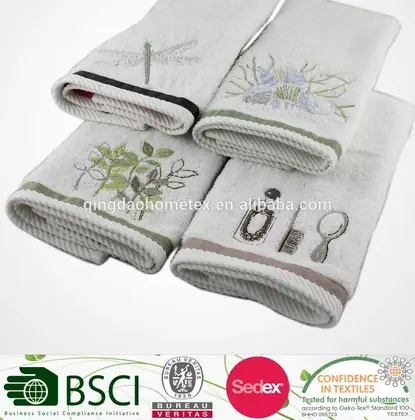 Four folded white towels with embroidered dragonfly, botanical, and toiletry designs on a white background