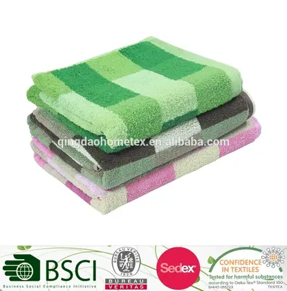 Stack of folded checkered towels in green, brown, and pink on a white background with certification logos along the bottom.