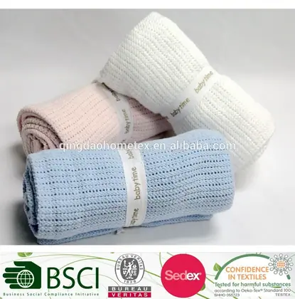 Three rolled knitted baby blankets in white, pink, and blue with woven labels, certification logos below.