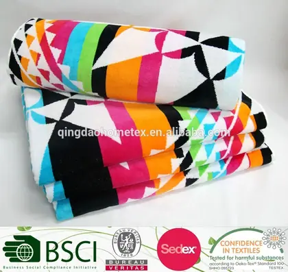 Stack of colorful geometric-patterned beach towels with certification logos banner below