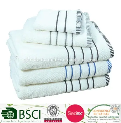 Stack of folded white towels with grey and blue striped borders on a white background