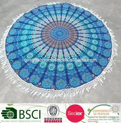Round blue mandala tapestry with fringe tassels laid flat on a gray floor, shown from above
