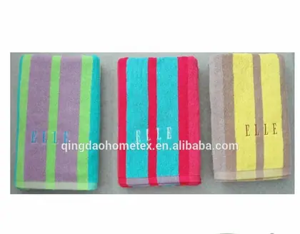 Three striped terry towels in purple-green, pink-turquoise, and yellow-brown with embroidered text, shown with certification logos
