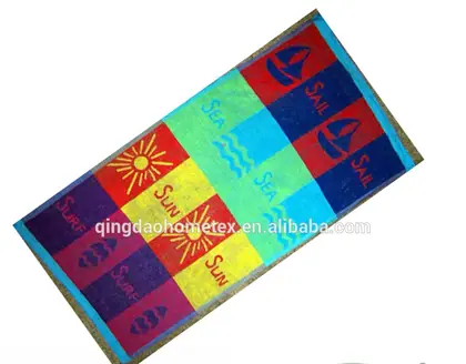 Colorful beach towel with sun, sailboat, and sea-themed blocks in red, blue, yellow, and green, shown diagonally with BSCI and Confidence in Textiles logos below
