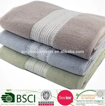Stack of three folded cotton towels in taupe, blue, and green with decorative woven borders