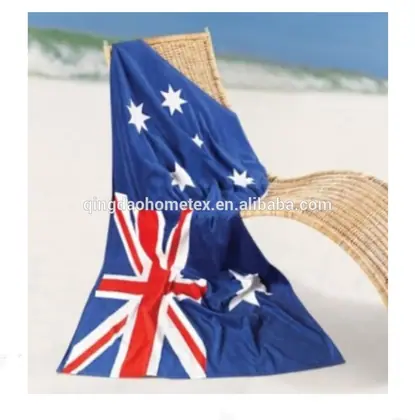 Blue flag-patterned beach towel with Union Jack and star design draped over a wicker chair on a sandy beach