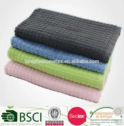 Stack of four folded waffle-weave kitchen towels in gray, blue, green, and pink on a white background