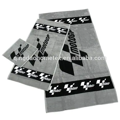 Three grey woven towels in graduated sizes with black checkered MotoGP logo borders, laid flat on white background