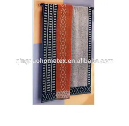 Three decorative towels with geometric borders in navy, orange, and gray hanging on a rod