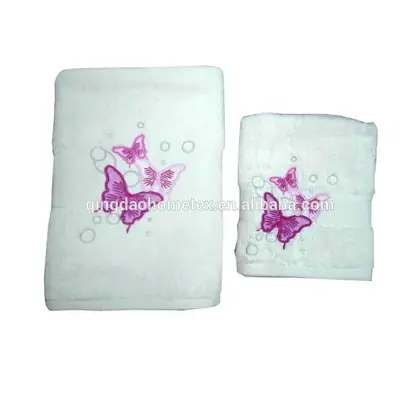 Two white towels with pink butterfly embroidery and bubble motifs on a plain background