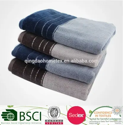 Stack of four folded towels in blue, grey, and brown with darker borders on a white background