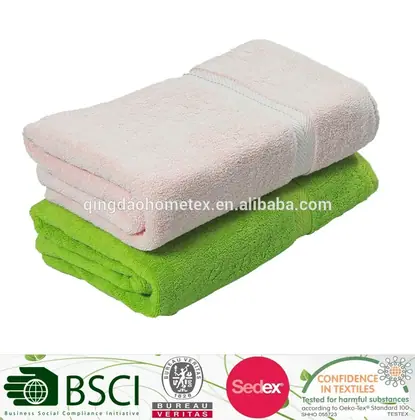 Folded white towel stacked on a folded green towel against a white background