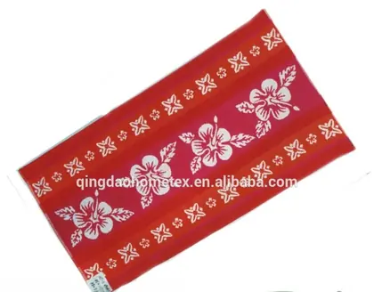 Red beach towel with white hibiscus flower print, shown diagonally on white background