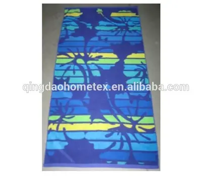 Rectangular beach towel with blue, green, and yellow floral stripe pattern lying flat on a gray floor