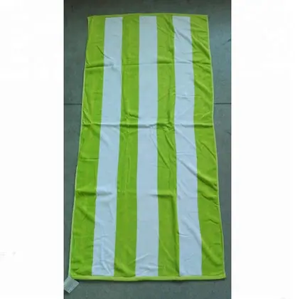 Green and white striped beach towel laid flat on a grey floor