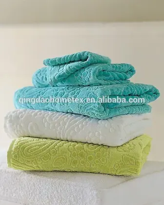 Stack of folded jacquard towels in turquoise, white, and green on a white surface