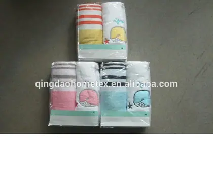 Three packaged kids towel sets with striped and whale-embroidered towels on a grey concrete floor