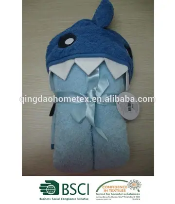 Blue shark-themed hooded baby towel, folded and tied with a light blue ribbon, on a wooden surface