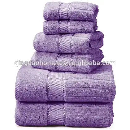 Stack of six folded purple terry cotton towels in assorted sizes on a white background