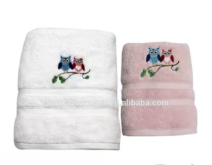 Folded white and pink towels with embroidered owl designs on branches, with BSCI and Confidence in Textiles logos below