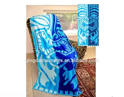 Blue and light blue printed beach towel with tiki-style pattern draped over a chair, with inset detail of the pattern