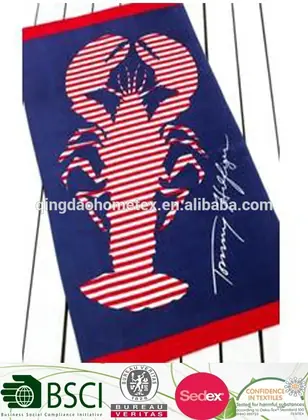 Navy blue beach towel with red and white striped lobster design and red border, lying on white slatted surface