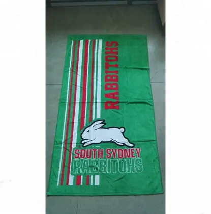 Green beach towel with printed rabbit logo and red and white stripes lying on a tiled floor