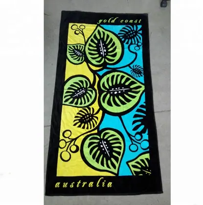 Black beach towel with colorful leaf print and 'gold coast australia' text, photographed on concrete