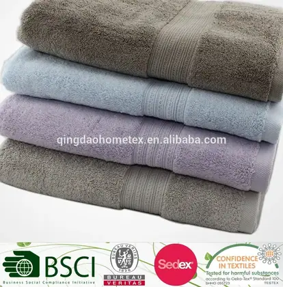 Stack of folded terry towels in grey, blue, and lavender on a white background