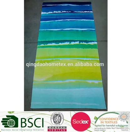 Striped beach towel in blue, green, and yellow gradient colors laid flat