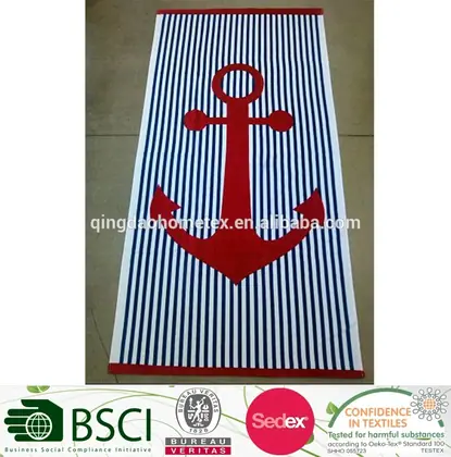 Navy and white striped beach towel with a large red anchor design laid flat on a concrete floor