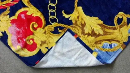 Folded navy blue blanket with ornate red, gold, and yellow baroque-style print and white underside