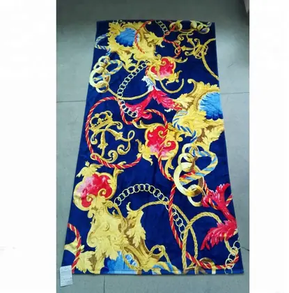 Beach towel with baroque-style print of gold chains, crowns and floral ornaments in yellow, red and blue on a navy background