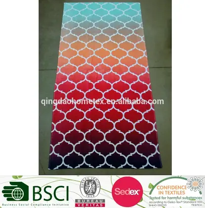 Rectangular beach towel with white quatrefoil pattern over a teal-to-orange-to-red ombre gradient, laid flat