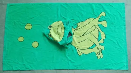 Green hooded children's towel with a yellow frog design laid flat